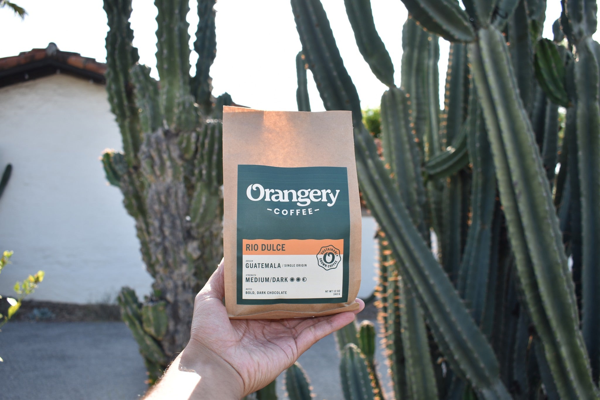 An image of a bag of coffee with cactus plants and a adobe building in the background