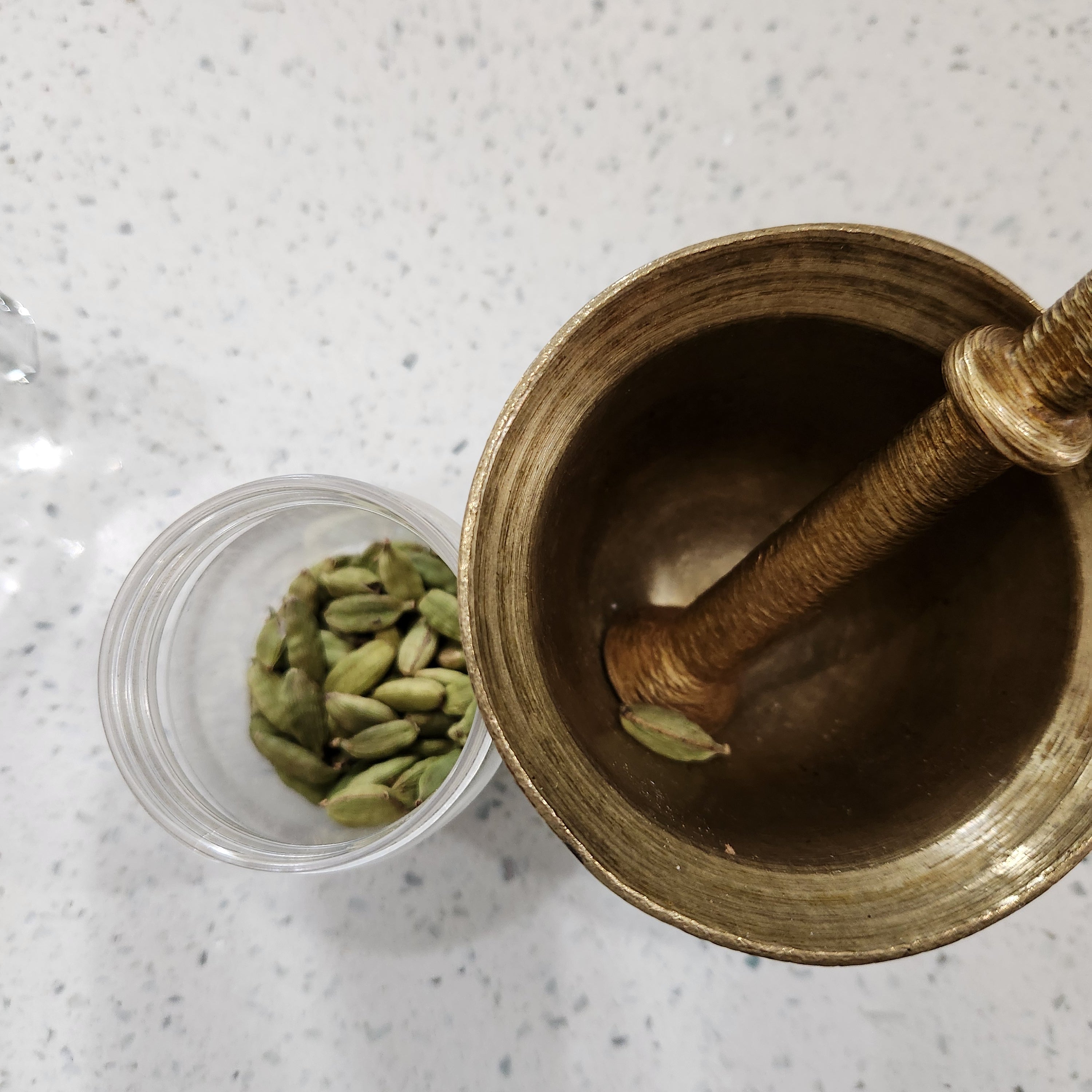 An image of a bottle of cardamom and mortar and pestle